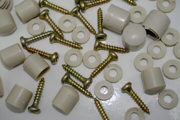 Scattered screws, plastic caps, and washers on white surface