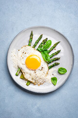 Fried egg with green asparagus and grated parmesan cheese for breakfast