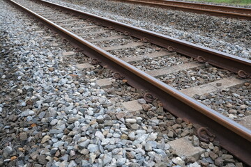 Detailed view of parallel railway tracks with metal rails and wooden sleepers surrounded by crushed stone ballast for support.

