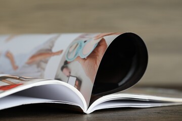 One open magazine on wooden table, closeup