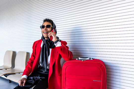 Stylish non-binary person talking on phone while waiting at airport