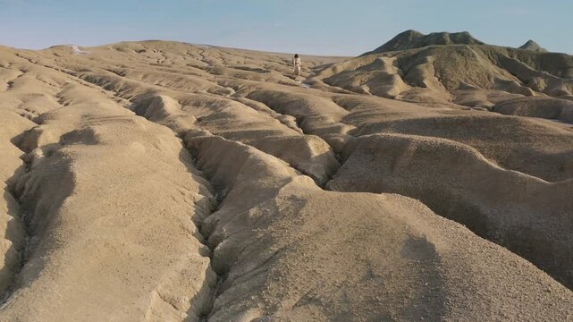 A long-haired man dressed in a white robe, descending the sandy hills of the Judean Desert. Tracking shot