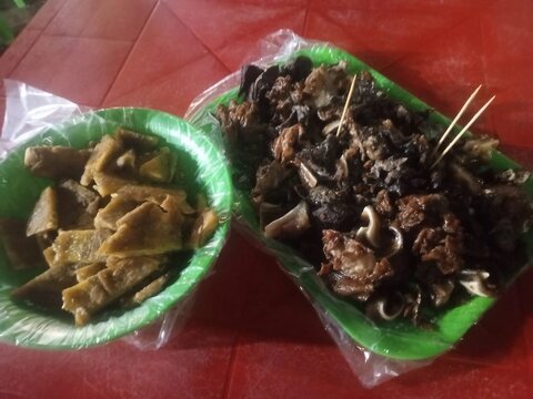 Gekochte Fleischst&uuml;cke und Innereien auf gr&uuml;nen Plastiktellern serviert, traditionelle Stra&szlig;engerichte mit Spie&szlig;en und Beilagen.. Kolumbien