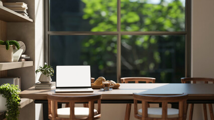 White screen laptop aside breads on plate and coffee on wooden table in a dining room or living room