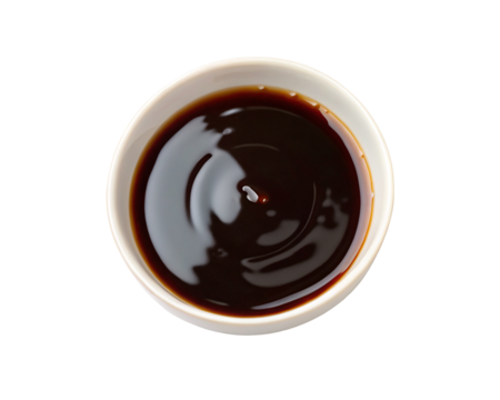 Top view of dark soy sauce in white bowl against black background for cooking ingredient focus