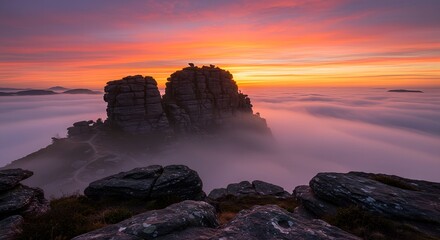 Breathtaking view of dramatic rock formations emerging from a sea of clouds at sunrise, perfect for themes of adventure, nature, and majestic landscapes.