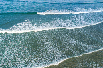 Fototapeta premium Drone view of the surf on a sunny day, a peaceful and scenic seascape.