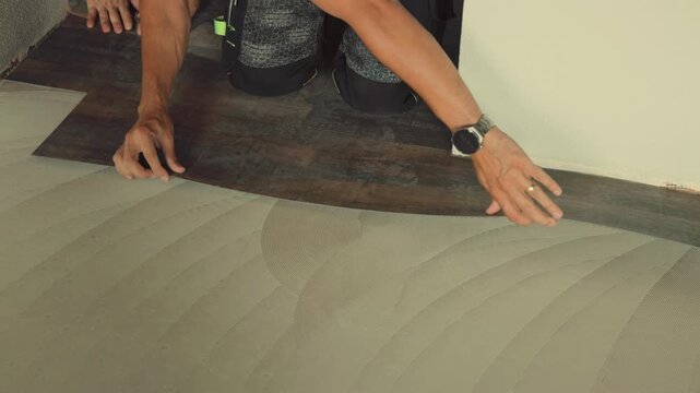 Construction worker installing vinyl laminate flooring