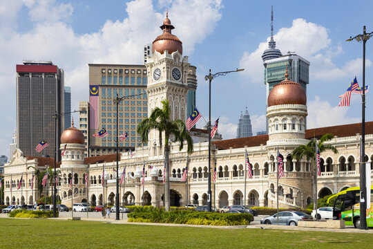 View of historical Sultan Abdul Samad Building with its copper domes under a partly cloudy sky, framed by modern skyscrapers, Kuala Lumpur, Federal Territory of Kuala Lumpur.