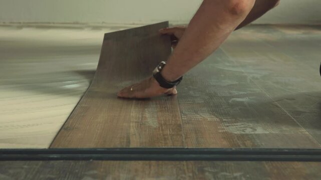 Construction worker installing vinyl laminate flooring