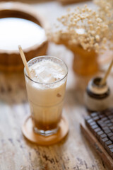 A glass of iced milk tea or coffee aside painting brush on working table in a pottery studio or cafe