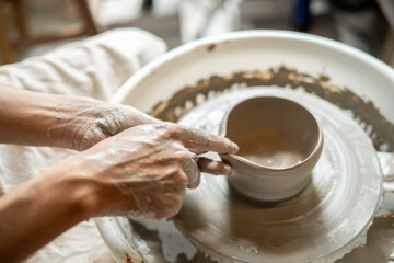 Close up pottery artist making a clay tea brewing bowl on spinning throwing wheel in class or studio