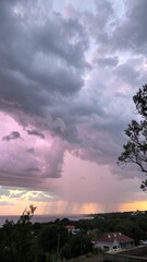Obraz premium Dramatic sunset sky with purple and pink clouds over a distant landscape