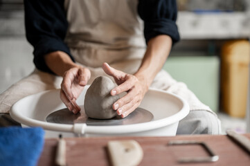 Close up of pottery artist's hands holding clay body on spinning throwing wheel in a class or studio