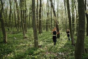Fototapeta premium Women jogging through a sunlit forest trail