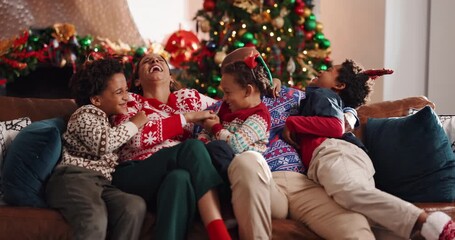 Laughing, family and celebration of Christmas, home or bonding on festive season, love and December. Happy, man and woman with children on Xmas holiday, tickling and fun with kids, lounge and house