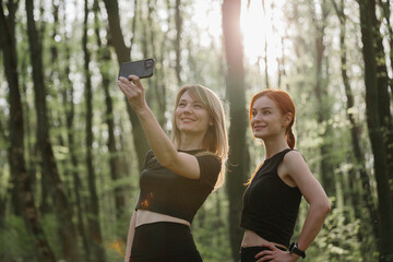 Obraz premium Two women taking a selfie in the woods after exercising