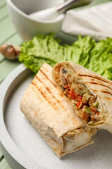 Plate of tasty shawarma with lettuce on green wooden background