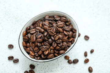 Bowl with coffee beans on light background