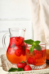 Jug and glass of infused water with strawberry on table