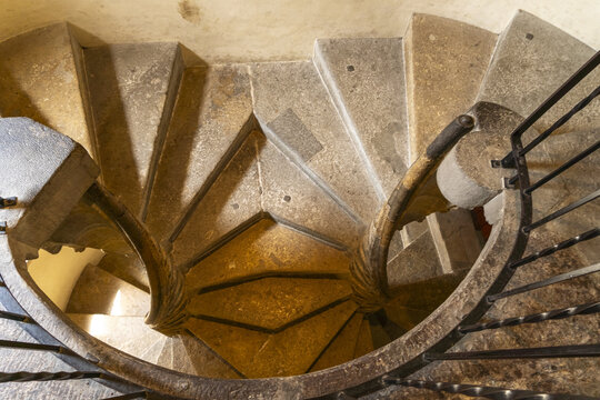 View of a stone spiral staircase ascends in a mesmerizing dance of curves and shadows, a timeless testament to architectural ingenuity, Graz, Steiermark, Austria.