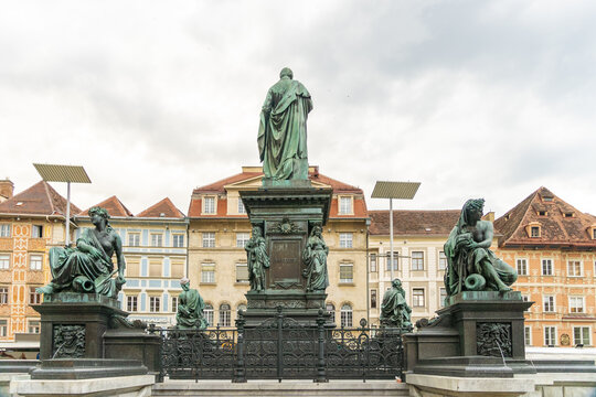View of the Erzherzog Johann fountain, a striking bronze monument against a backdrop of colorful buildings and overcast skies, Graz, Steiermark, Austria.