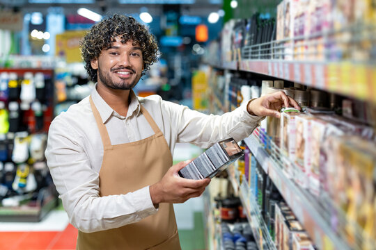 A friendly grocery store employee is seen stocking shelves and smiling at the camera.