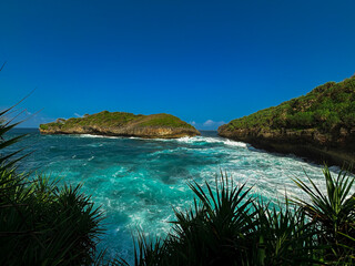 Fototapeta premium Seaside Serenity: A breathtaking coastal vista unfolds, where turquoise waters meet rugged land, under a vibrant blue sky, inviting the viewer to immerse themselves in nature's spectacle.