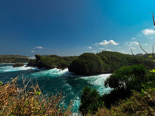 Coastal Paradise: A breathtaking coastal view where emerald waters meet rocky cliffs, showcasing nature's awe-inspiring artistry under a clear, azure sky.