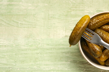Bowl with tasty pickled cucumbers on green wooden background