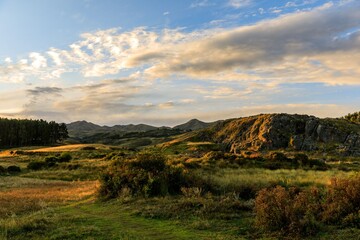 Fototapeta premium Scenic landscape with rolling hills and sunset sky.