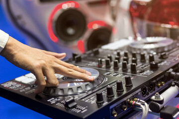 Close up view of  DJ's hand controls on the deck at night. DJ spinning and scratching music in concert using mixing console on a turntable in sound recording studio.