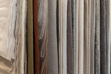 A collection of various fabric swatches in neutral tones. The fabrics include linen, cotton, and silk, arranged neatly in vertical rows.