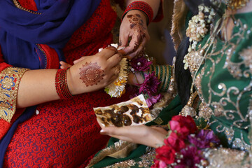 Intricate henna design being applied to a hand during a wedding ceremony