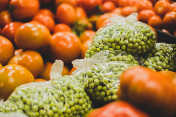 Guisantes verdes frescos en bolsa y tomates. Parada de mercado. 