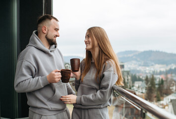 Young couple sharing a moment on balcony, enjoying hot drinks