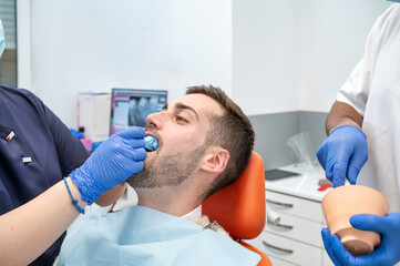 Man receiving oral dental impression from two dentists in modern clinical setting
