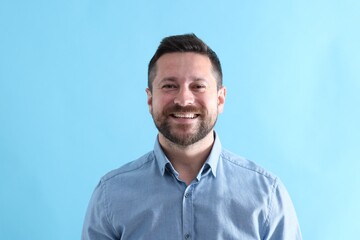 Handsome man laughing on light blue background
