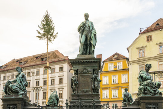 View of the Erzherzog Johann fountain stands tall as a bronze figure amidst ornate sculptures and colorful buildings, Graz, Graz, Austria.