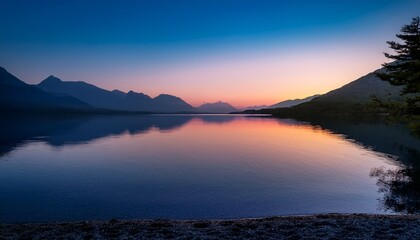 Fototapeta premium a serene lake at dusk perfectly still water reflecting the gradients of a beautiful sunset with mountains in the background