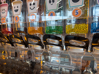 Bright and colorful candy dispenser with various sweet treats in vibrant bins. Perfect for retail environments, candy shops, or self serve candy stations to attract customers with a fun design