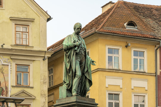 View of a bronze statue stands tall against the backdrop of aged buildings with orange rooftops, creating a striking contrast, Graz, Graz, Austria.