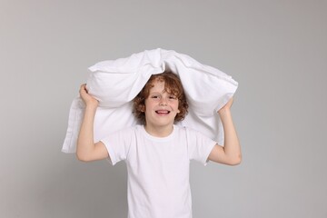 Cute little boy in pajamas with pillow on grey background © New Africa