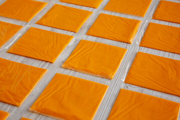 American Cheese Slices in Wrappers, side view.