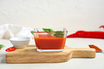 Glass bowl of tomato sauce with basil on white background