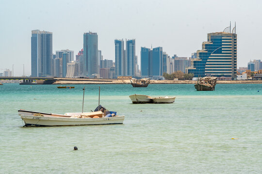 Manama, Bahrain - 29 May 2022: View of traditional dhows bobbing in the turquoise waters against the backdrop of the modern skyline, where the Bahrain World Trade Center rises majestically.