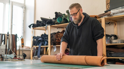Caucasian bearded man working as a tanner in a workshop. 