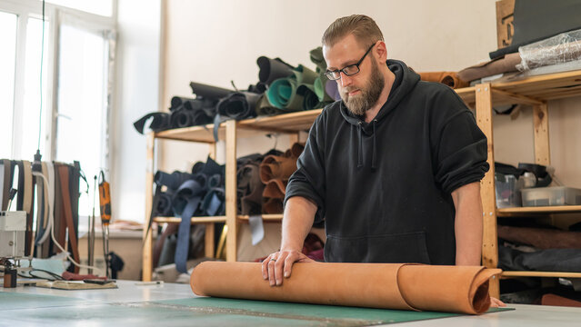Caucasian bearded man working as a tanner in a workshop. 