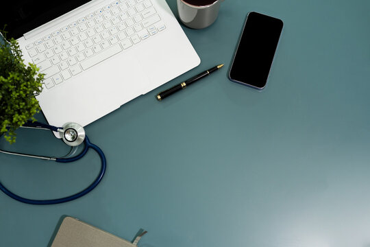 Top view of doctor desk table with stethoscope, coffee, Medical gown and notebook with pen.