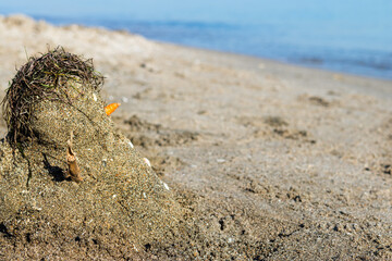 Sandman. A little snowman made with sand at the beach. Blurred background. 